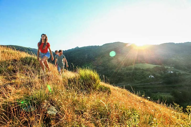 Amigos paseando por una colina iluminada por el sol poniente en Haute-Loire, Auvergne