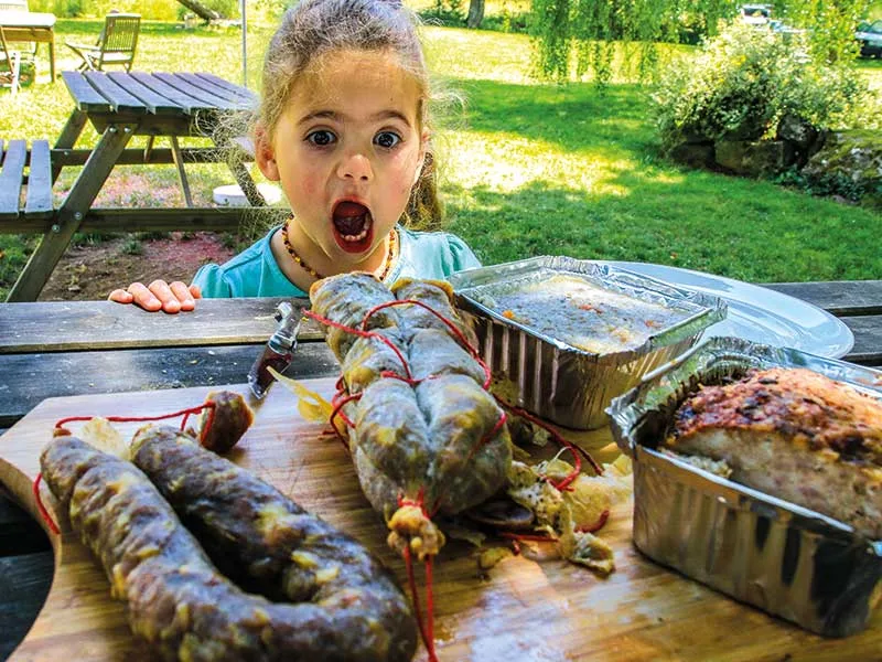 Petite fille bouche bée devant des saucissons