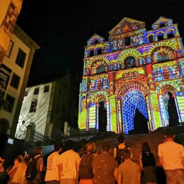 La folla contempla la cattedrale Notre-Dame-du-Puy illuminata dal Puy en Lumières