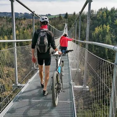 A cyclist and pedestrians walk on the Himalayan footbridge of Haute-Loire