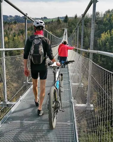 A cyclist and pedestrians walk on the Himalayan footbridge of Haute-Loire