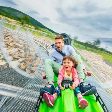Un padre y su hija se divierten paseando en trineo por el parque Lugik de Estables, Alto Loira