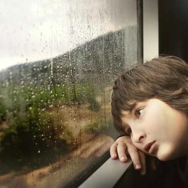 Een kind kijkt naar de regen door het treinraam in de Haute-Loire