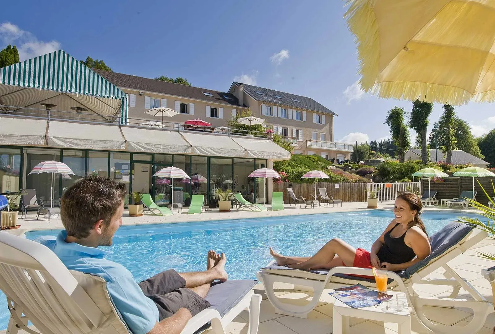 Un couple se détend au bord de la piscine extérieur de l'hôtel Bel Horizon au Chambon-sur-Lignon en Haute-Loire