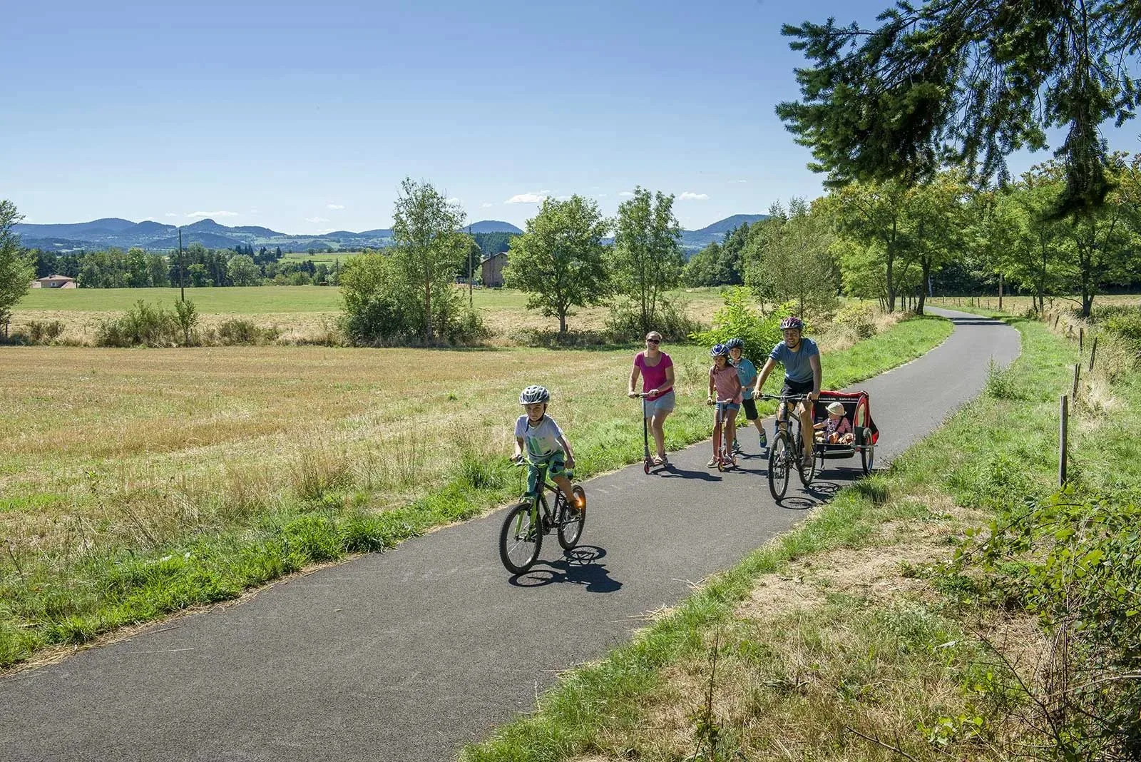 A family rides bicycles, scooters and rollerblades on the via fluvia in Haute-Loire