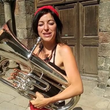 Una donna sorridente tiene un corno in mano per il Festival du Monastier, il luogo dell'ottone in Alta Loira, Alvernia