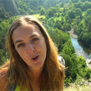 Una mujer habla con el río y el bosque desde un ángulo bajo en Alto Loira, Auvernia