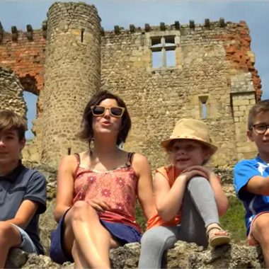 Een gezin zit op een lage muur van het kasteel van Rochebaron in de Haute-Loire, Auvergne