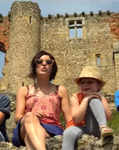Een gezin zit op een lage muur van het kasteel van Rochebaron in de Haute-Loire, Auvergne