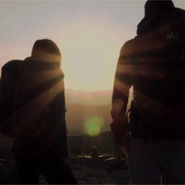 Due persone in controluce guardano il sole tramontare in cima a una montagna nell'Alta Loira, in Alvernia