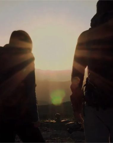 Twee mensen kijken in tegenlicht naar de zonsondergang op de top van een berg in de Haute-Loire, Auvergne
