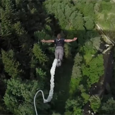 A man bungee jumps above the forest and river in Haute-Loire, Auvergne