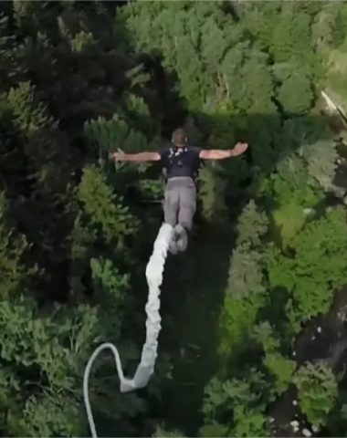 A man bungee jumps above the forest and river in Haute-Loire, Auvergne
