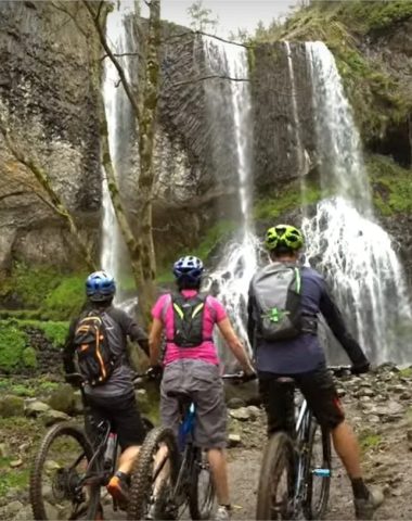 Los ciclistas de montaña admiran la cascada de Beaume en la Grande Traversée de la Haute-Loire, en Auvernia