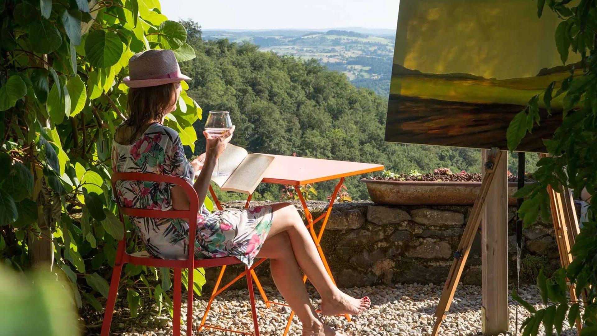 Een vrouw leest met een glas in haar hand en overweegt het uitzicht in Haute-Loire, Auvergne