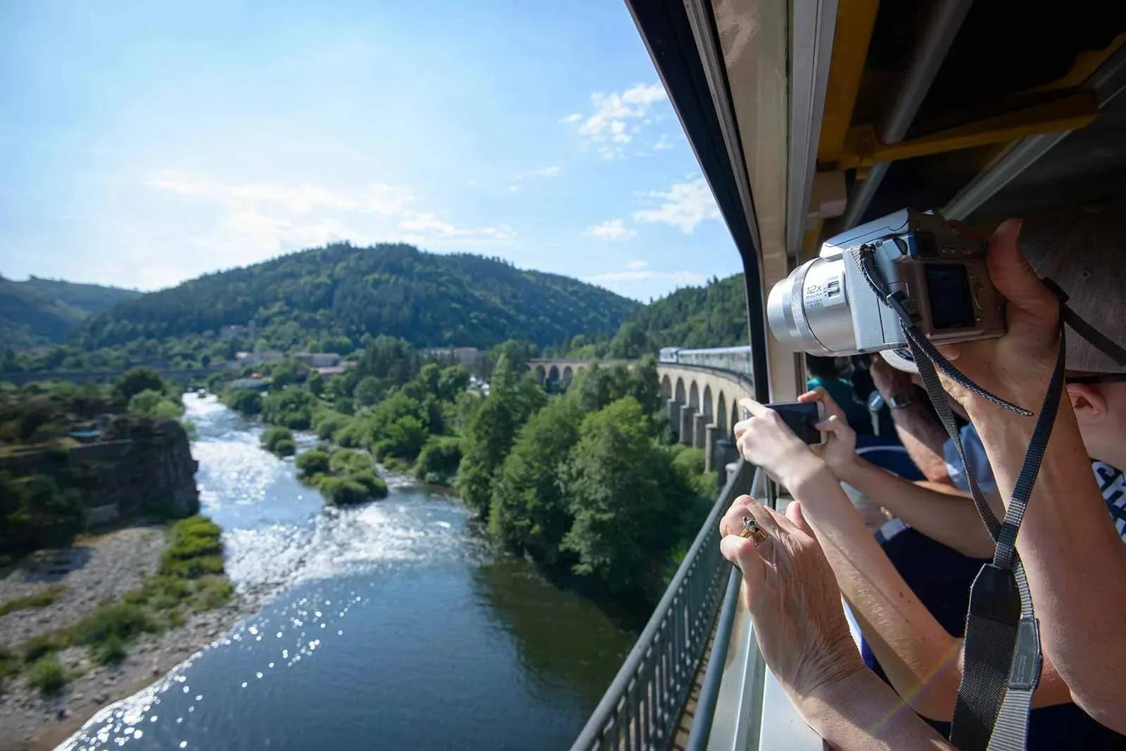 La gente en un tren toma fotos del río que pasa por debajo en Haute-Loire, Auvergne