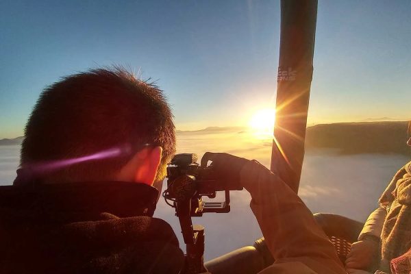 Ein Videofilmer filmt den Sonnenaufgang aus dem Korb eines Heißluftballons in Haute-Loire, Auvergne