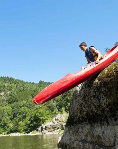 Un kayakista se desliza de una roca para ir al río en Haute-Loire, Auvergne
