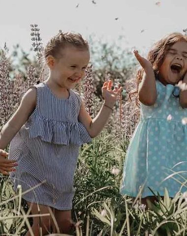 Zwei kleine Mädchen lachen auf einem blühenden Feld in der Haute-Loire, Auvergne