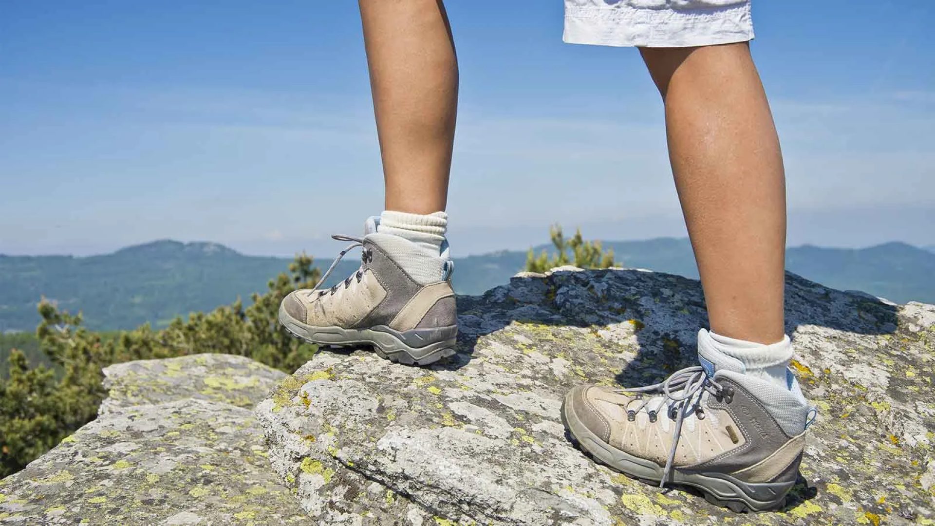 Legs of hikers on a rock with a view of the Haute-Loire mountains, Auvergne