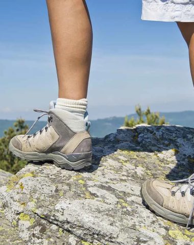 Gambe di escursionisti su una roccia con vista sulle montagne dell'Alta Loira, Auvergne