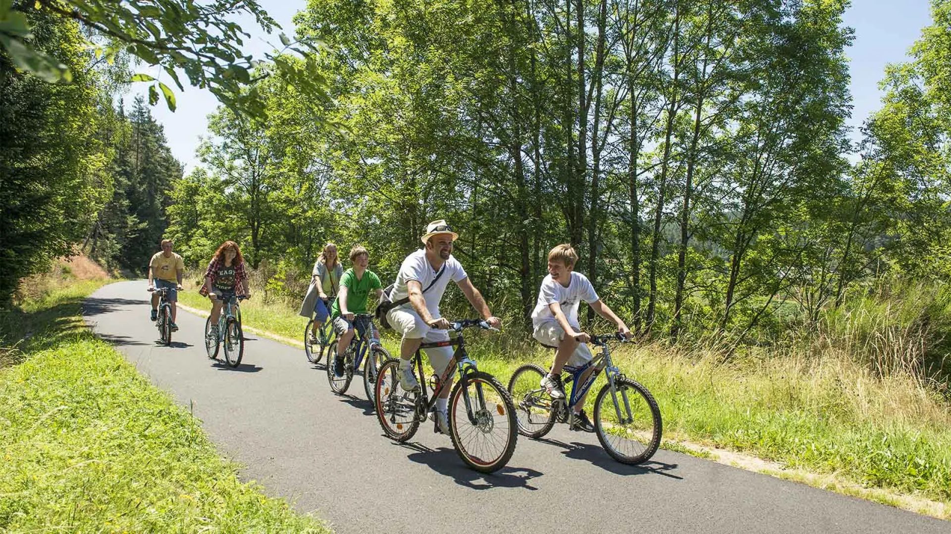 Une famille fait du vélo au soleil sur une route de Haute-Loire, Auvergne