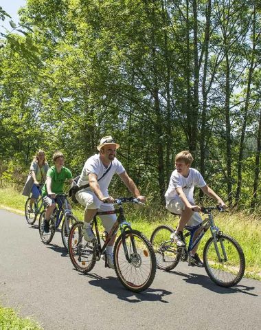 Une famille fait du vélo au soleil sur une route de Haute-Loire, Auvergne