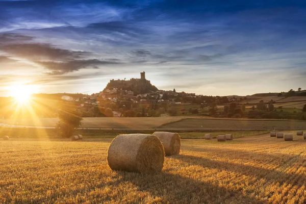 A setting sun over a field with the fortress of Polignac in the background in Haute-Loire, Auvergne