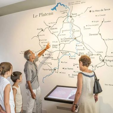 Una familia mira el mapa de la meseta de Vivarais Lignon en una pared del Lugar de la memoria en Chambon-sur-Lignon en Haute-Loire, Auvernia
