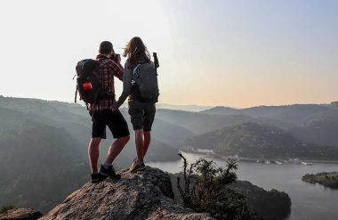 Una pareja de excursionistas observa el paisaje desde lo alto de una roca en Alto Loira, Auvernia