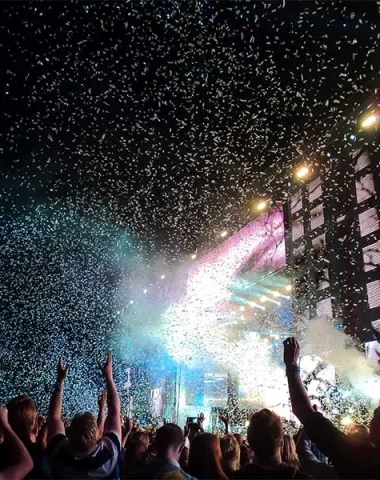 The crowd is going crazy in front of the stage of a night concert in Haute-Loire, confetti is flying